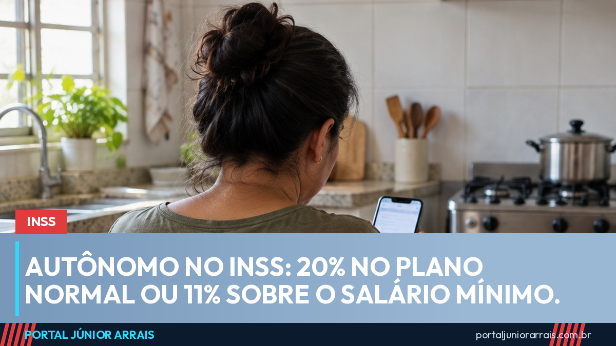 Mulher de costas sentada à mesa de uma cozinha arrumada, olhando o celular, com um carnê fechado e uma caneta sobre a mesa.